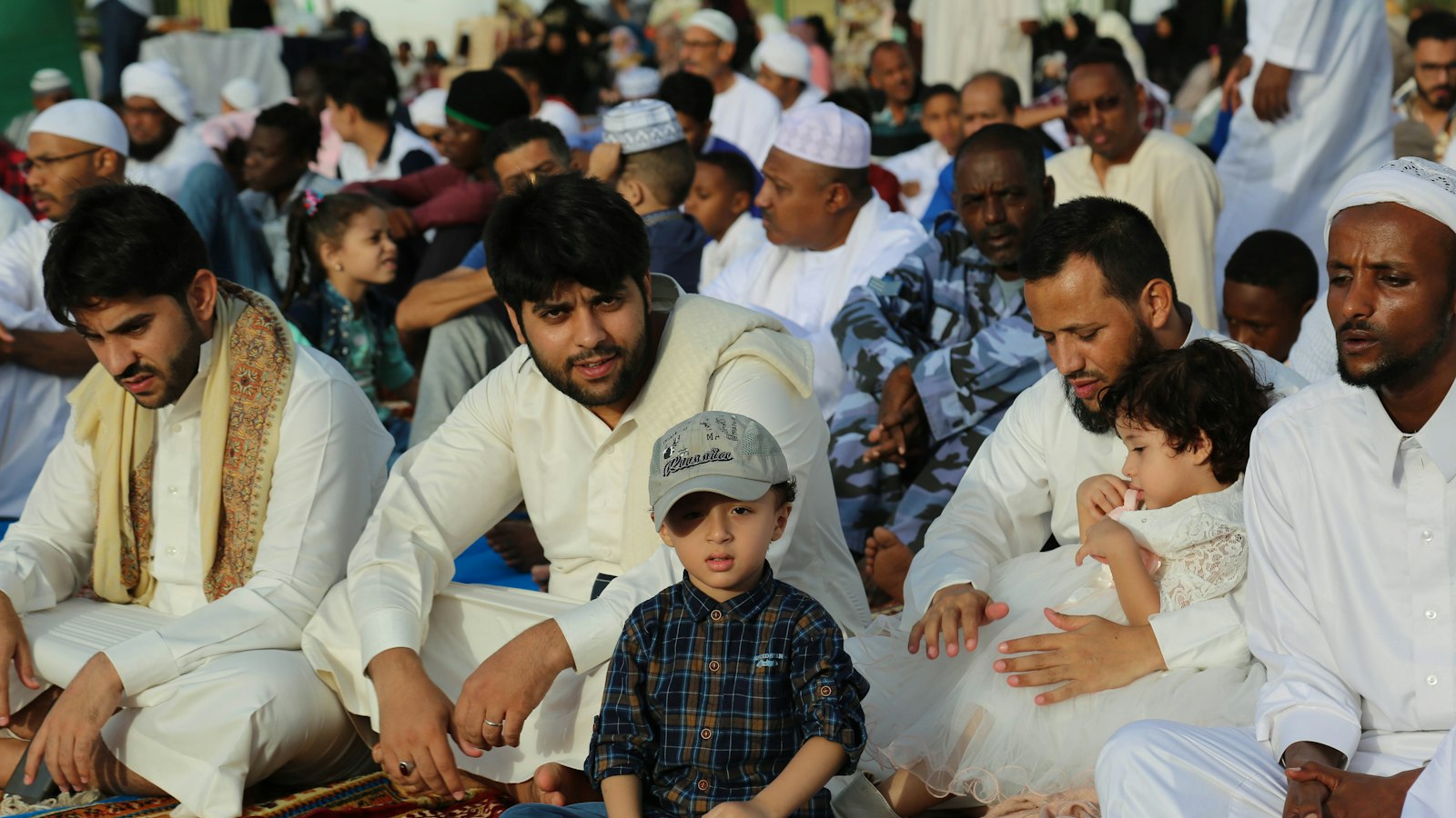 Men in white kurtas and topis seated together at a community gathering